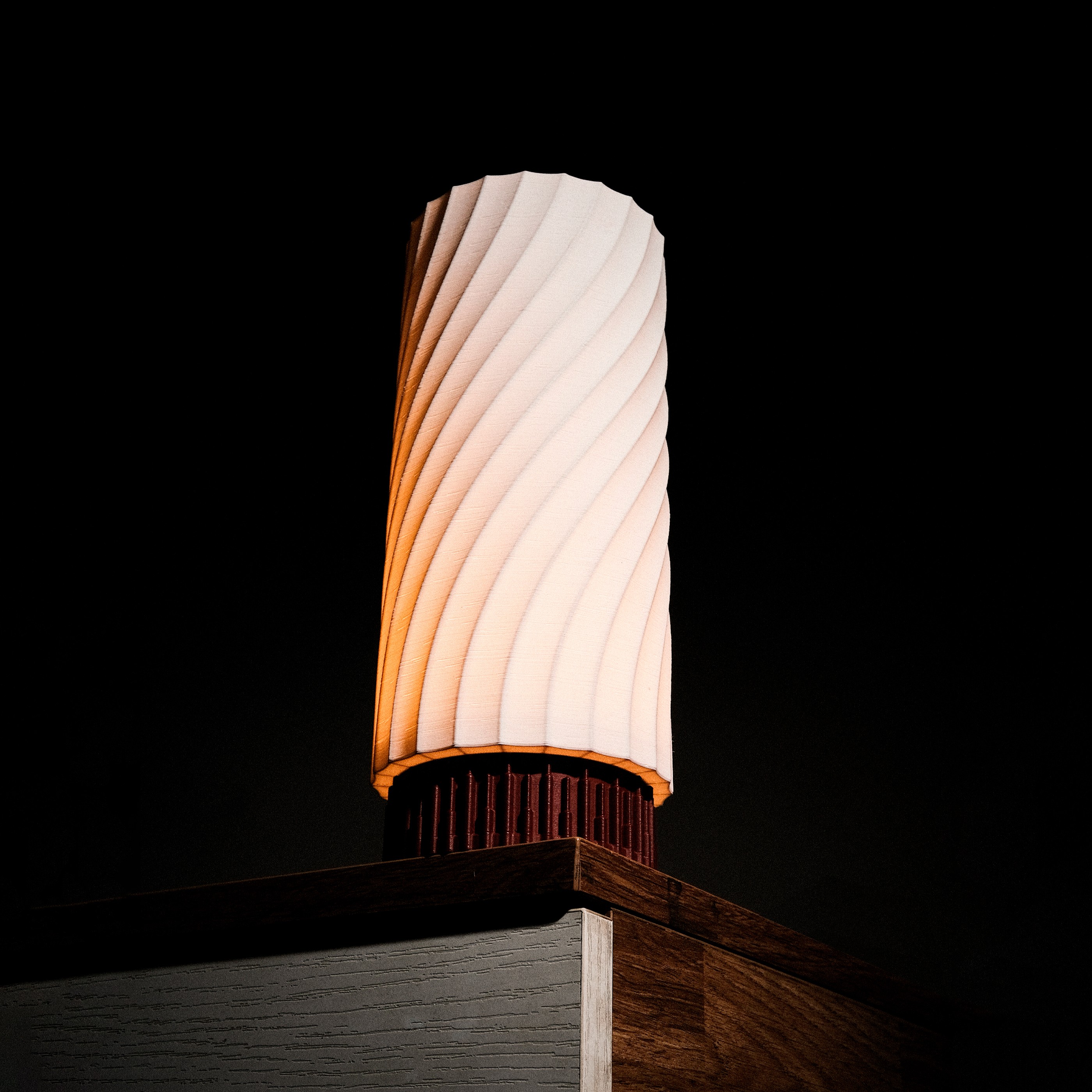 A close-up of a pink cocktail in a martini glass, set against a nighttime background with soft, blurred colors.