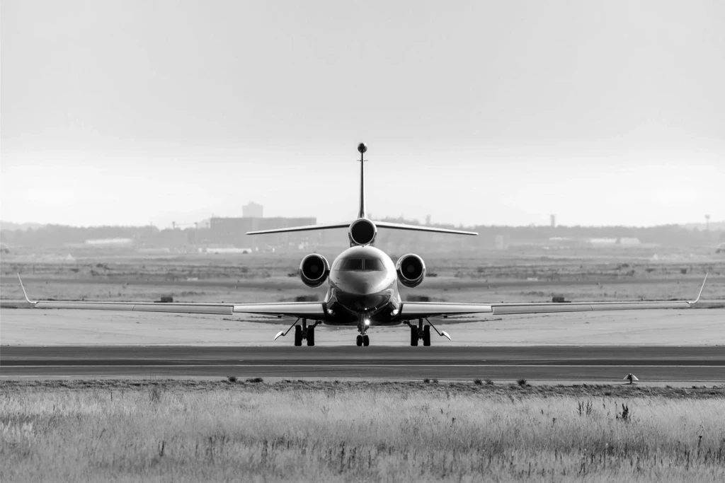A black and white image of an airplane on a runway, with a cloudy sky in the background.