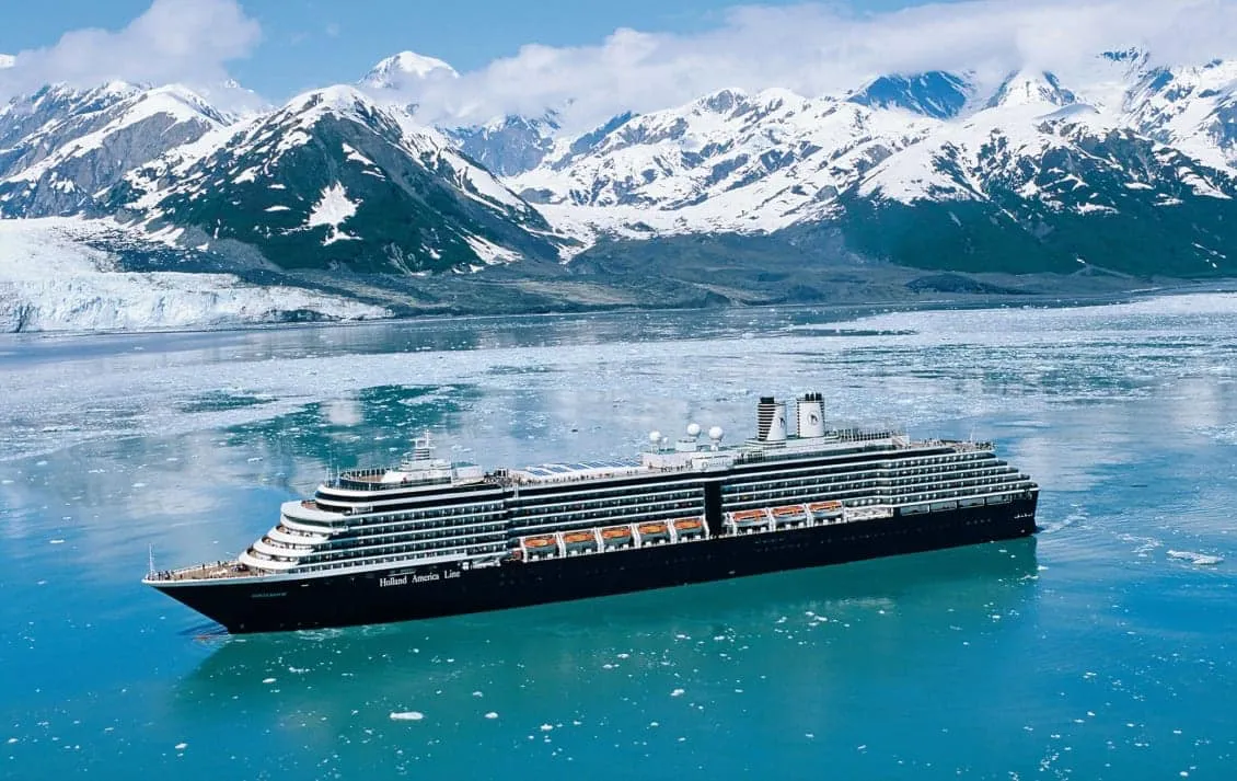Navio da Holland America navegando entre montanhas nevadas no Alasca