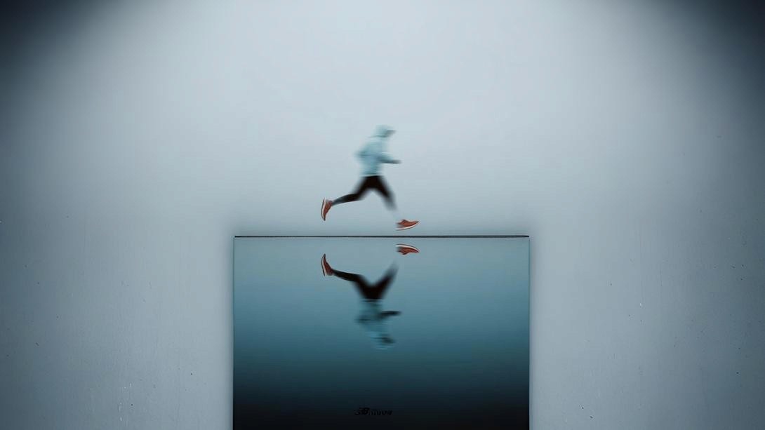 Modern office building with large windows reflecting a vivid orange sunset sky, silhouetted figure visible through the glass.