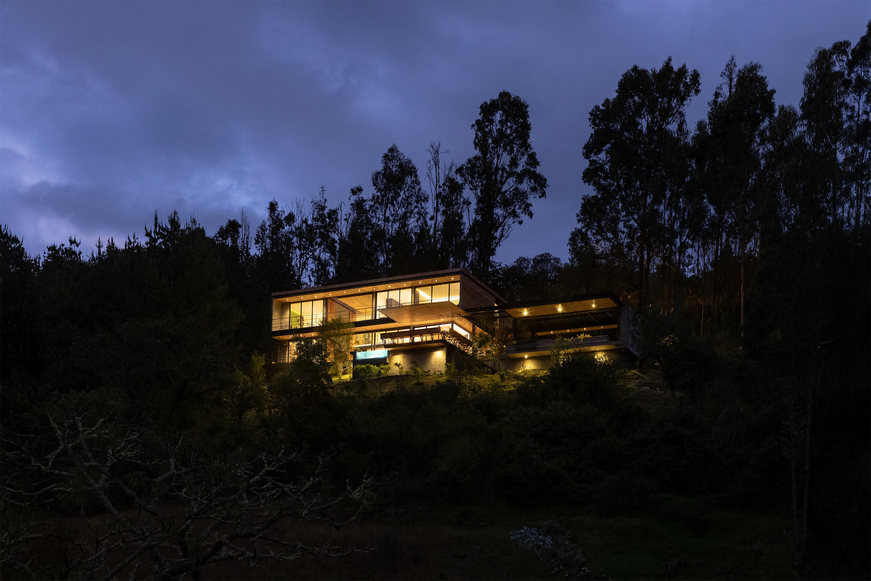 Casa moderna con voladizos en la montaña rodeada de vegetación en la noche