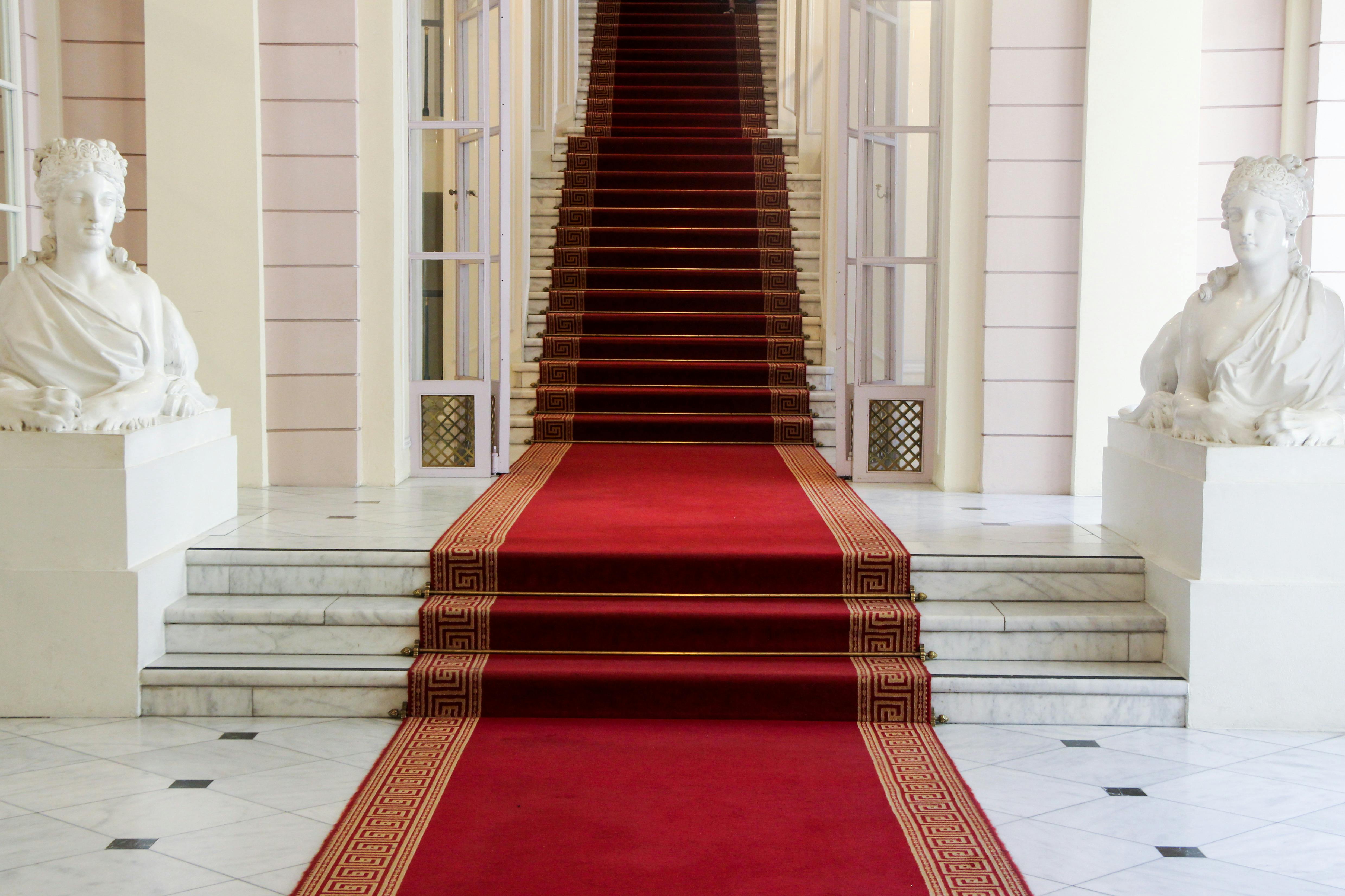 A beautiful traditional-style bedroom with paintings on the walls, a carpeted floor, and a chandelier overhead.