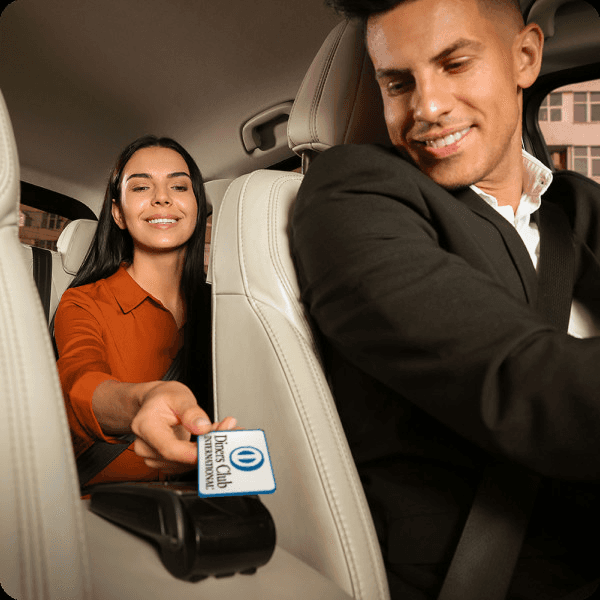 Woman tapping a Diners Club card on a payment terminal in the back of a taxi