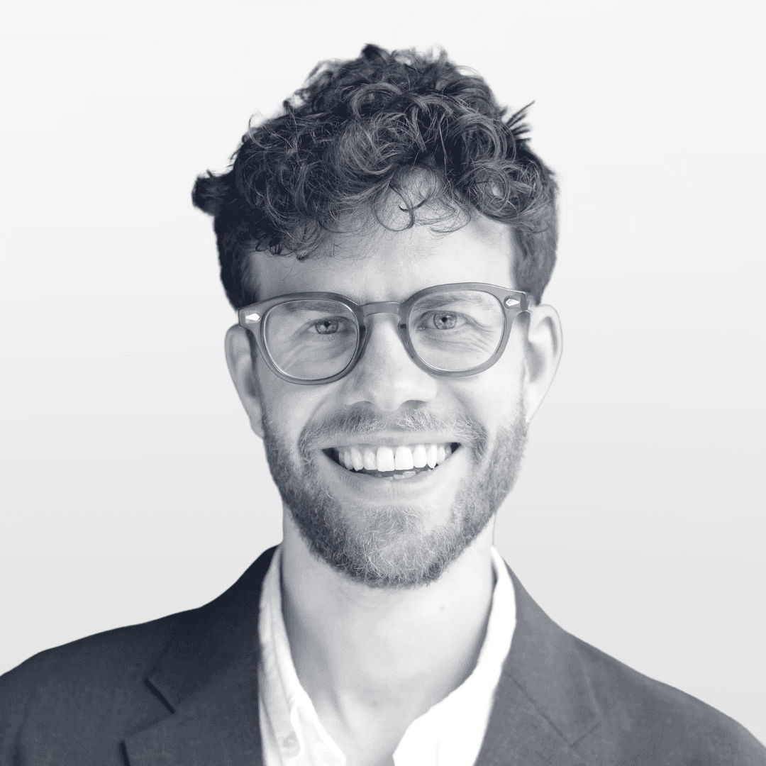 Portrait of a young man with short hair, wearing a dark t-shirt, against a plain background.