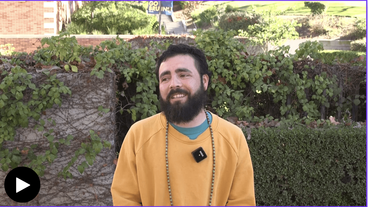 Noe Olivas wearing a yellow sweater, sitting outside 