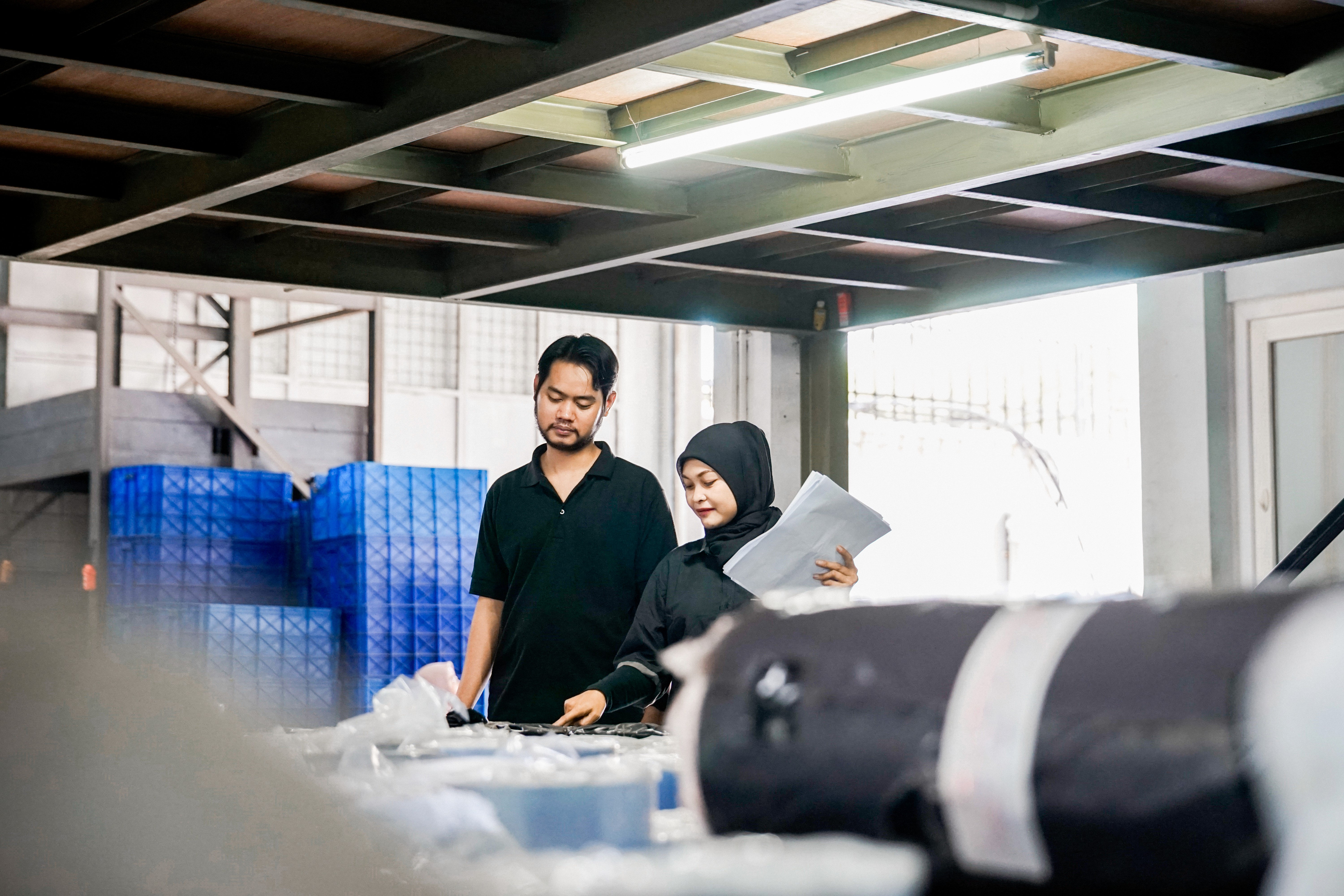 Dua orang pekerja sedang melakukan quality control pada kemasan plastik yang telah selesai diproduksi di area produksi pabrik kemasan. Pemeriksaan akhir kualitas kemasan plastik oleh dua karyawan di pabrik manufaktur, Proses QC kemasan blister plastik oleh tim quality control di industri pengemasan, Dua staf produksi sedang memeriksa kualitas hasil cetakan kemasan plastik siap kirim.