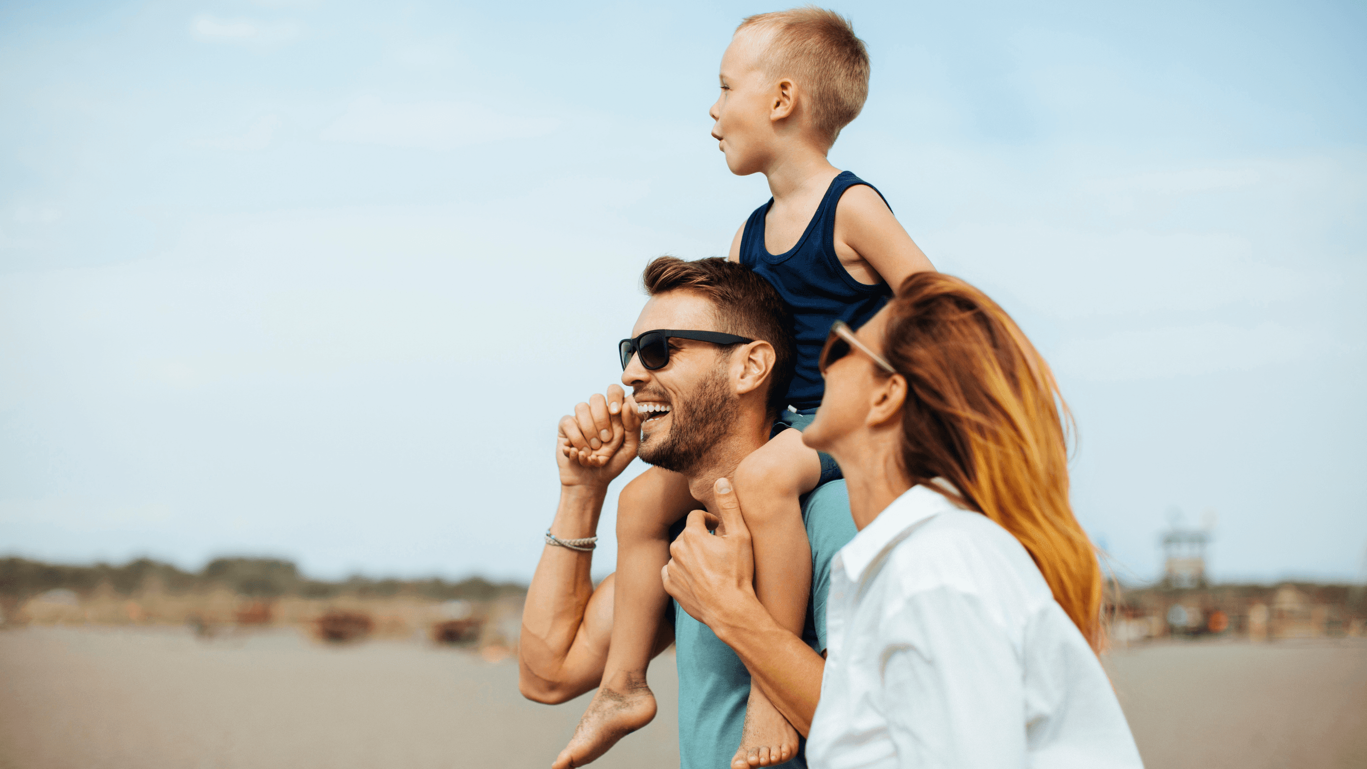 man in black and white striped long sleeve shirt holding baby in white shirt on beach