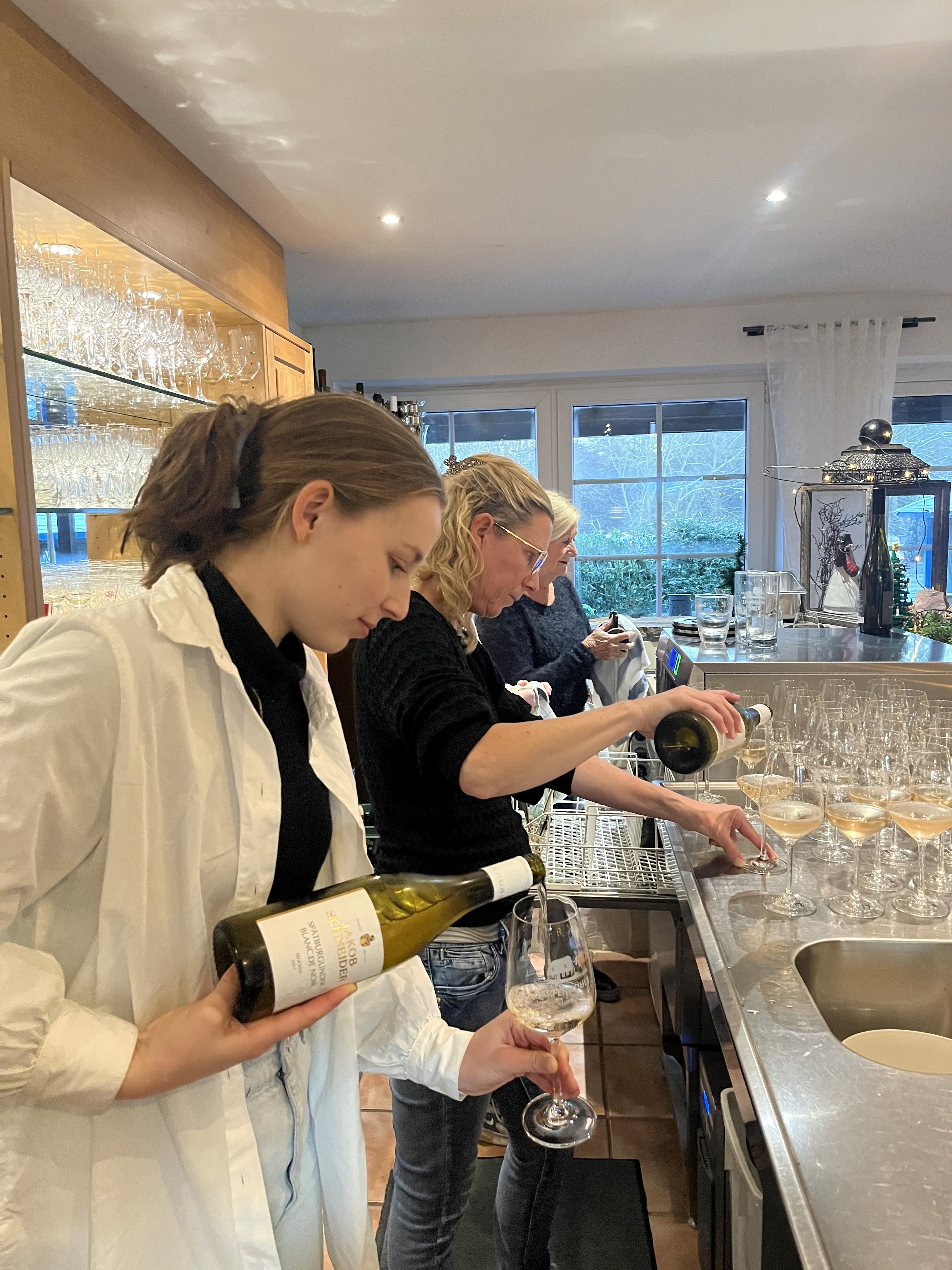 Zwei junge Damen schenken Wein ein.