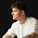 Young man working on laptop, focused expression. Indoor workspace.