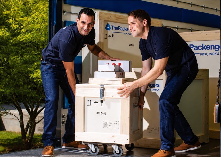 Professional art handlers loading specialized wooden crates and parcels marked with fragile handling icons, showcasing ThePackengers' secure transport and packaging solutions.