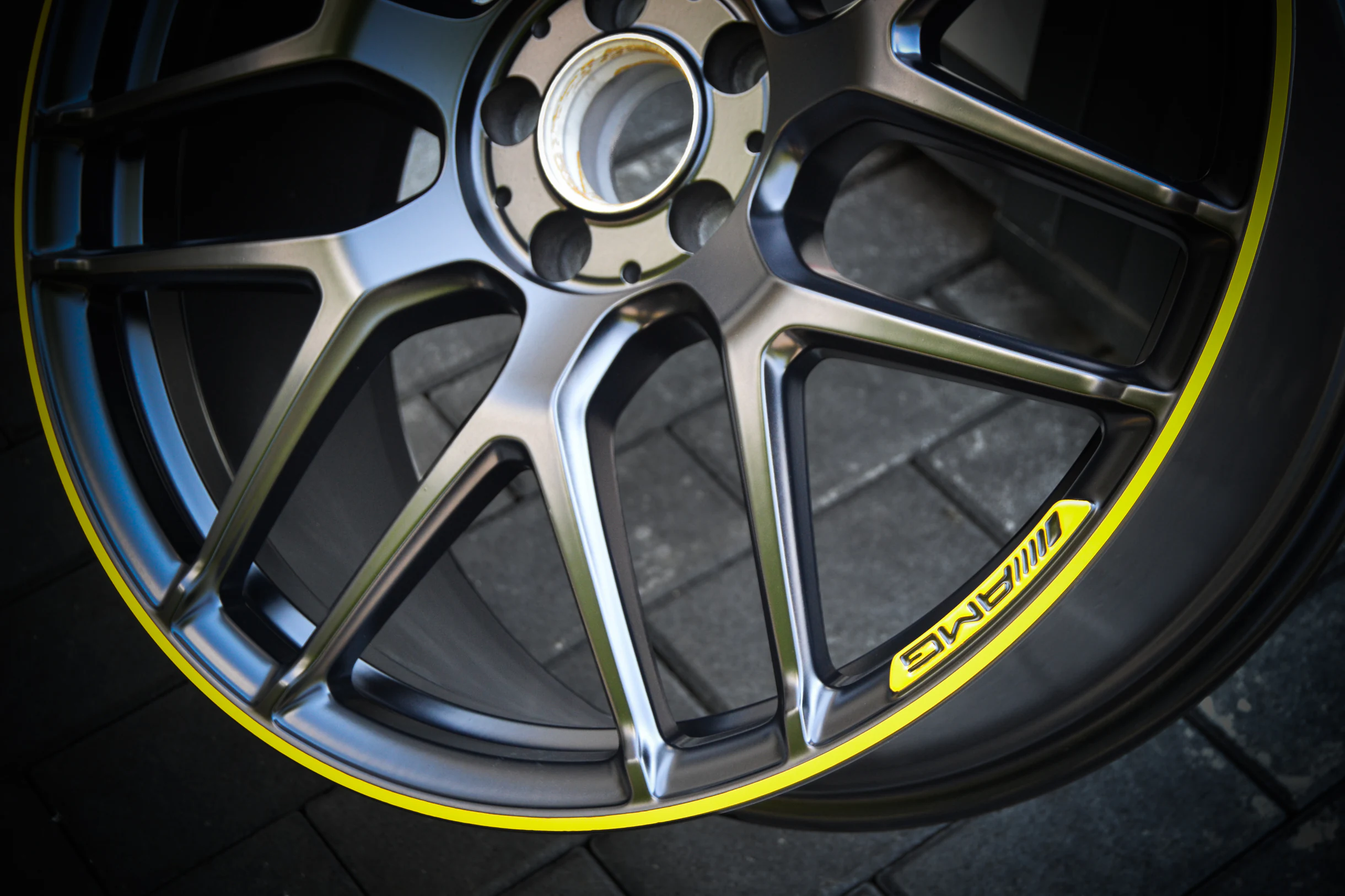 Detail der dunklen Speichen und des gelben Akzentrings einer AMG-Felge bei AT Plus.