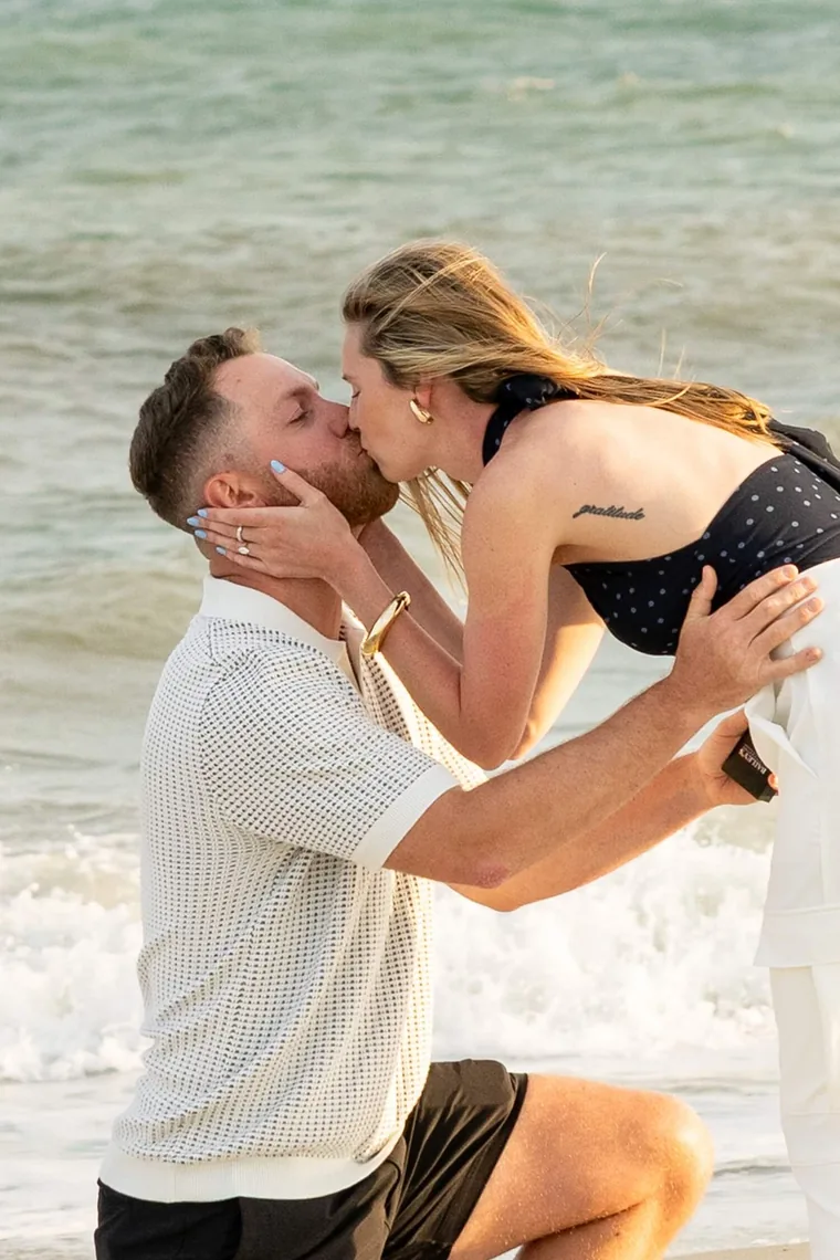 Couple kissing in the surf moments after a proposal, by Sioux Falls, SD engagement photographer Kelsey Lynn