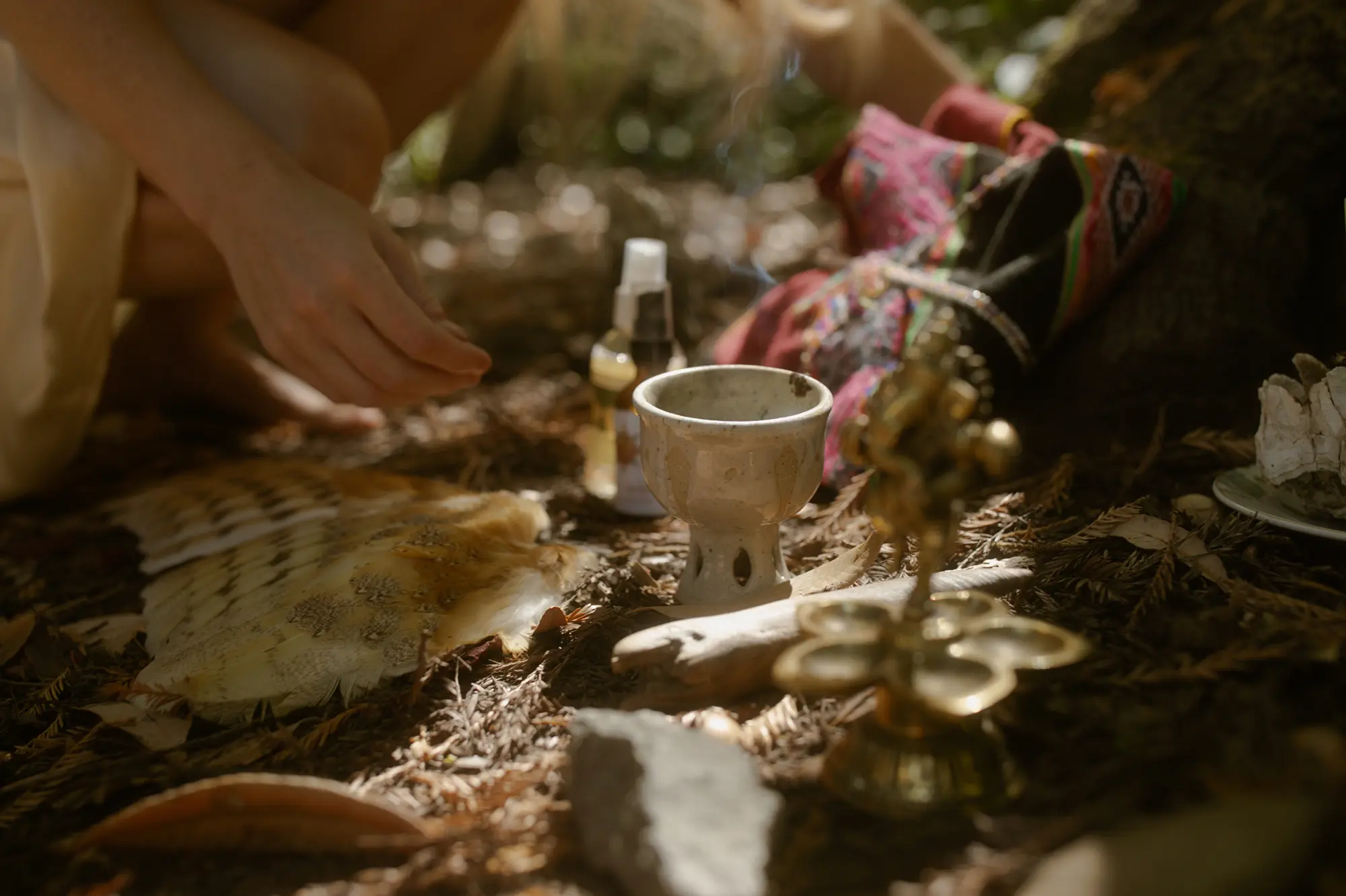 Close-up of sacred ceremonial altar with silver cup, feathers, flowers and ritual objects
