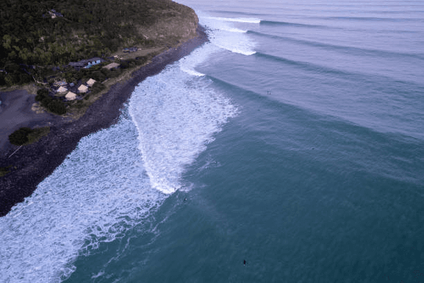 Raglan small coastal town with surfers on black sand beach in New Zealand