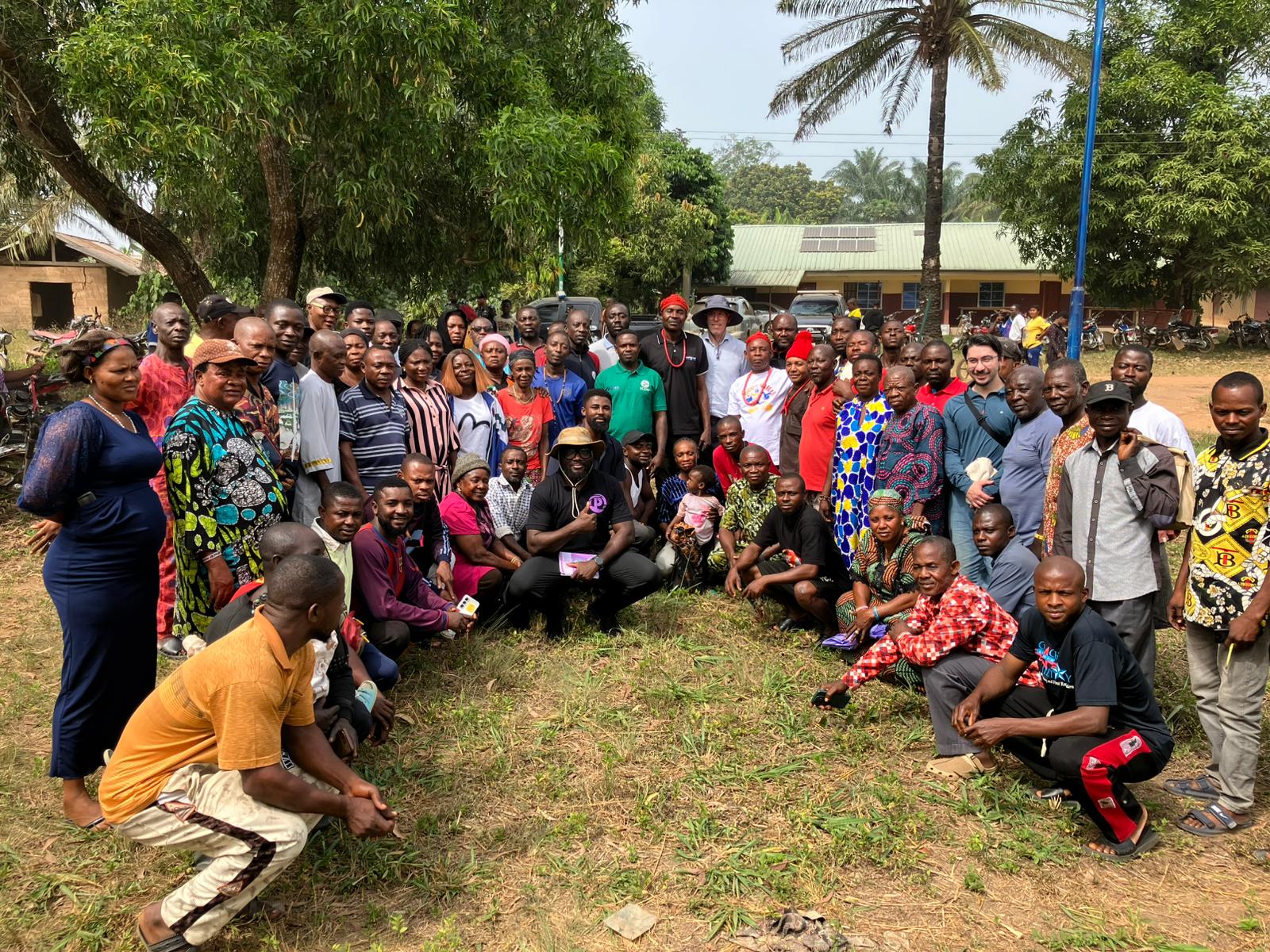 Une personne avec des lunettes et une barbe sourit chaleureusement tout en travaillant sur un ordinateur portable à un bureau. L'environnement est décontracté et relaxant, avec un arrière-plan neutre.