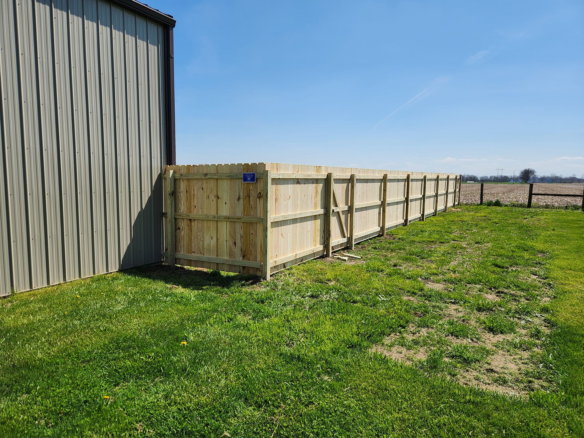 A serene outdoor seating area with two chairs, surrounded by lush greenery and a glassed-in structure.