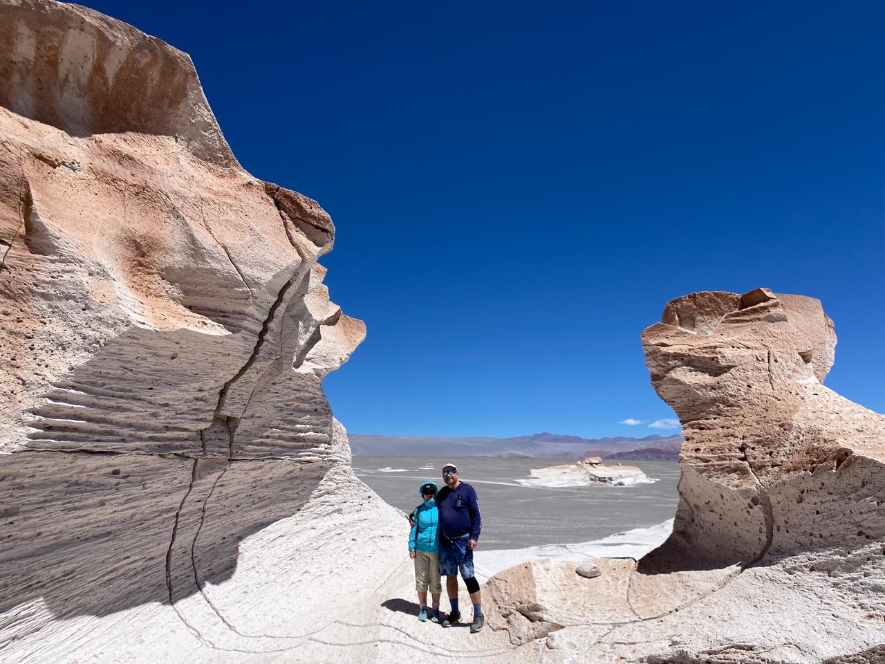 Mujer sentada sobre un tronco frente a una cascada doble en un bosque frondoso de Argentina.