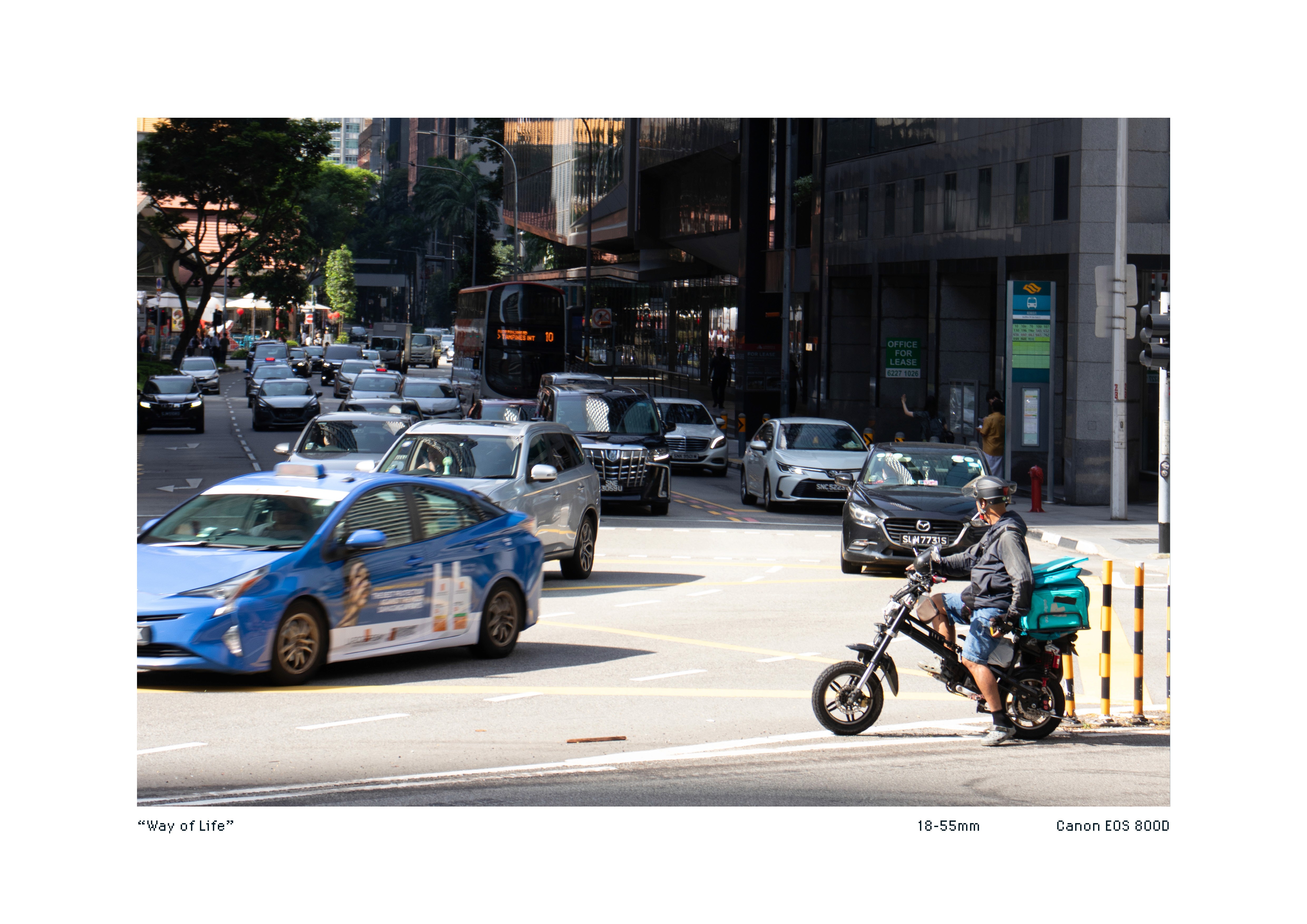Telephoto shot of a food delivery rider waiting for traffic to clear