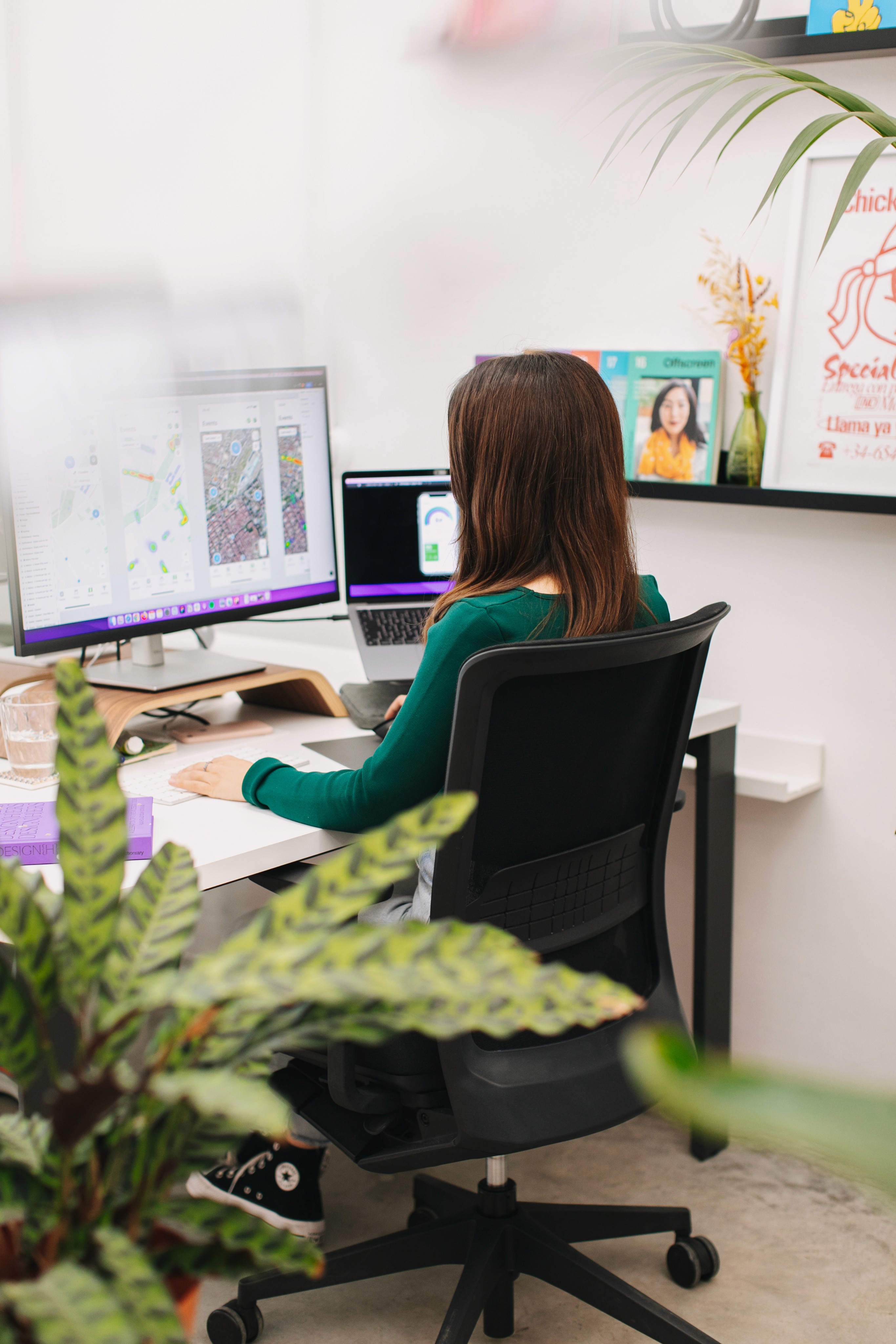 Girl working in an office on a design project in Figma, surrounded by plants and colorful decorations.