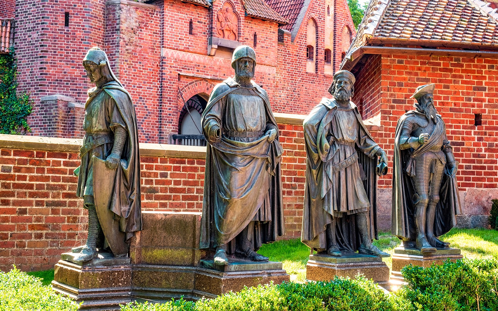 Statues of knights in front of Malbork Castle's red brick walls, Poland.