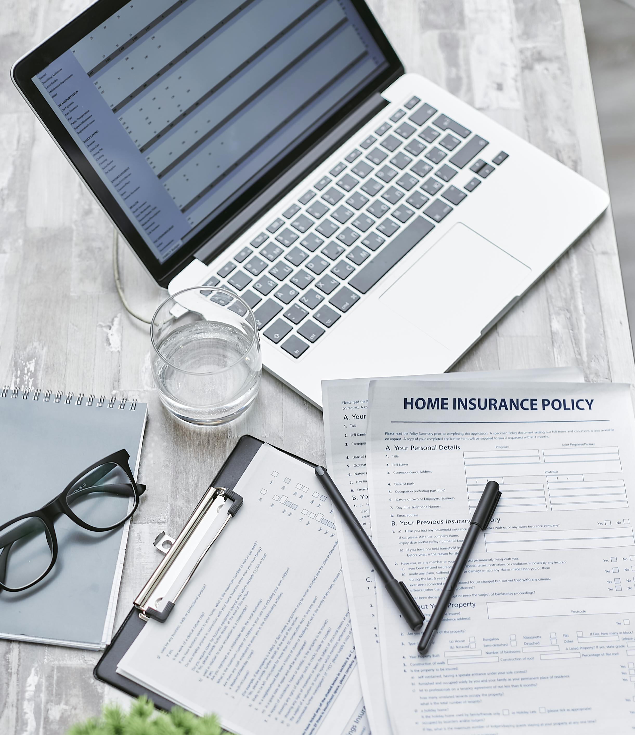 On the image: a laptop surrounded by paperwork, with an insurance policy prominently displayed, symbolizing Elevate Construction's commitment to being licensed and insured. Elevate Construction provides top-quality remodeling, renovation, siding, roofing, flooring, and project management services across Dutchess, Ulster, Orange, Rockland & Putnam Counties, including New Paltz, Gardiner, Highland, High Falls, Stone Ridge, Kerhonkson, Modena, Poughkeepsie, Kingston, Saugerties, Woodstock, Ellenville, Wallkill, Walden, Milton, Marlboro, and surrounding areas