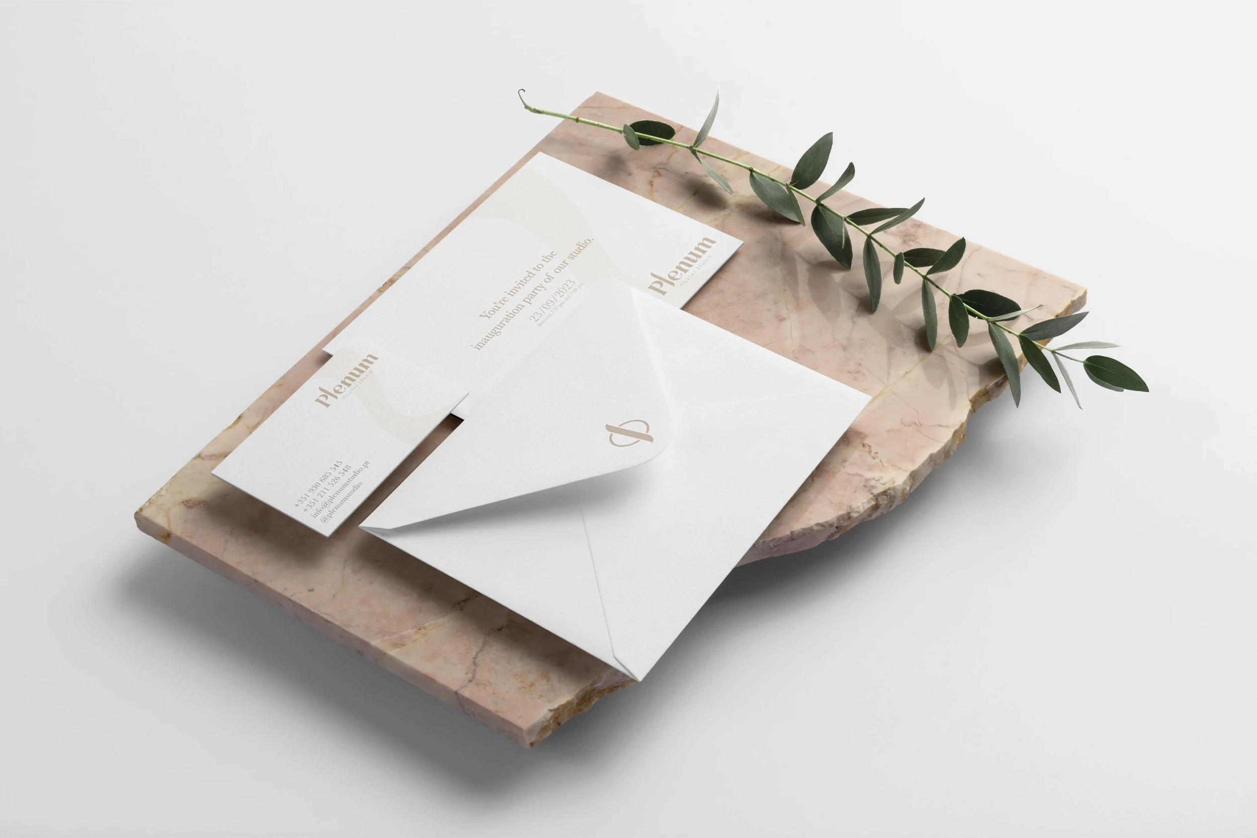 Plenum Pilates Studio stationery design including envelope, business card and printed materials displayed on natural stone surface, reflecting luxury wellness branding.
