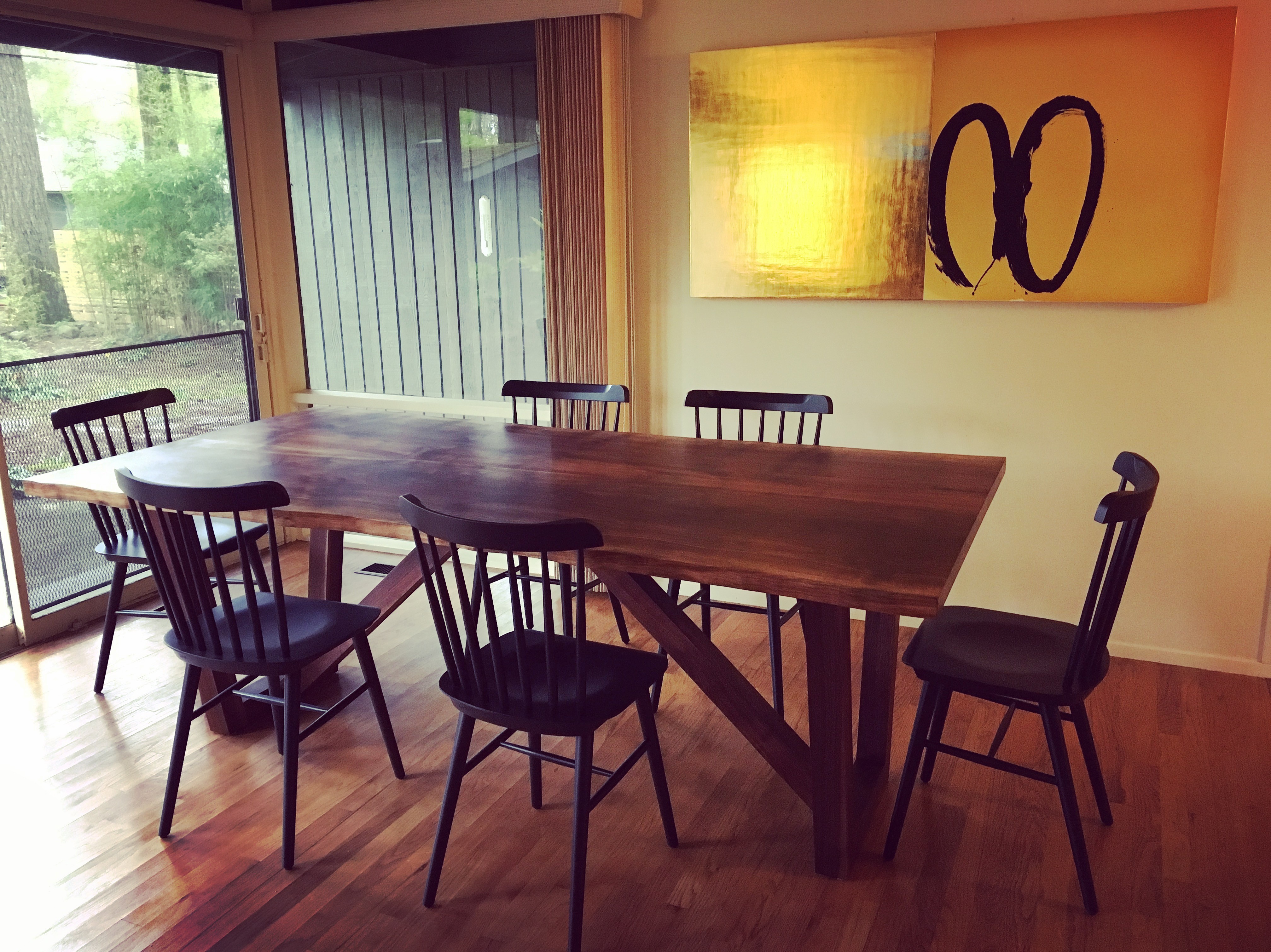 A large dark wood dining table is surrounded by black wooden dining chairs.