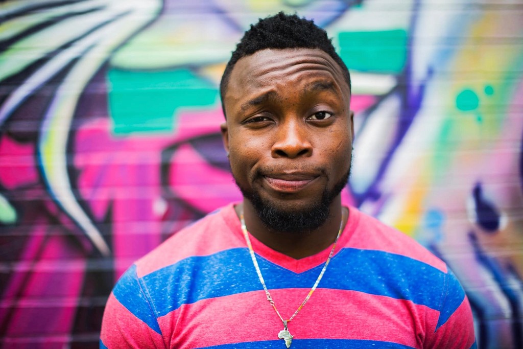 Man in pink and blue striped shirt with colorful graffiti background