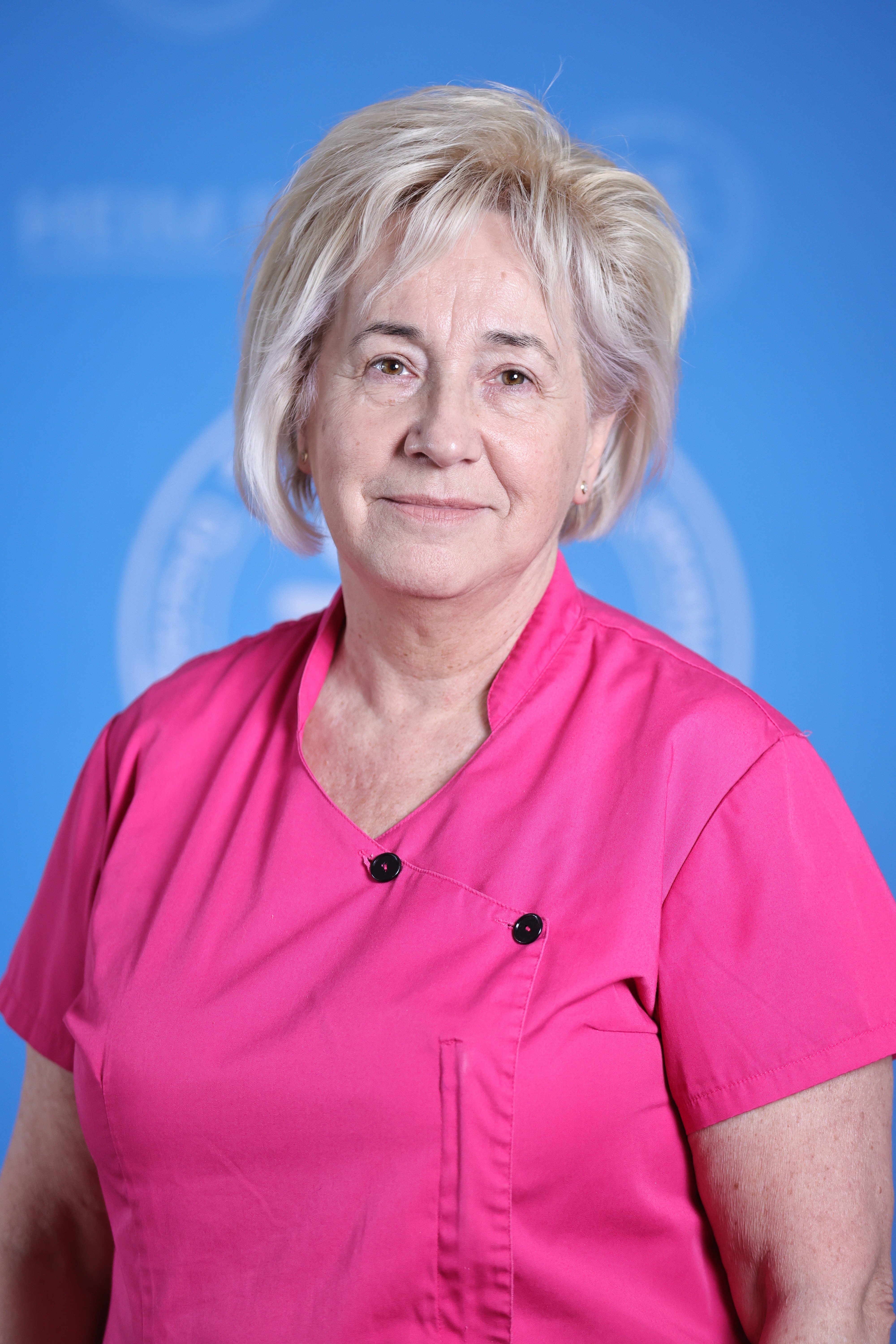 Ősz hajú nő rózsaszín orvosi ruházatban