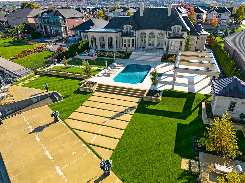 The manicured backyard of a gorgeous house with pool and AGL Grass North premium artificial grass.