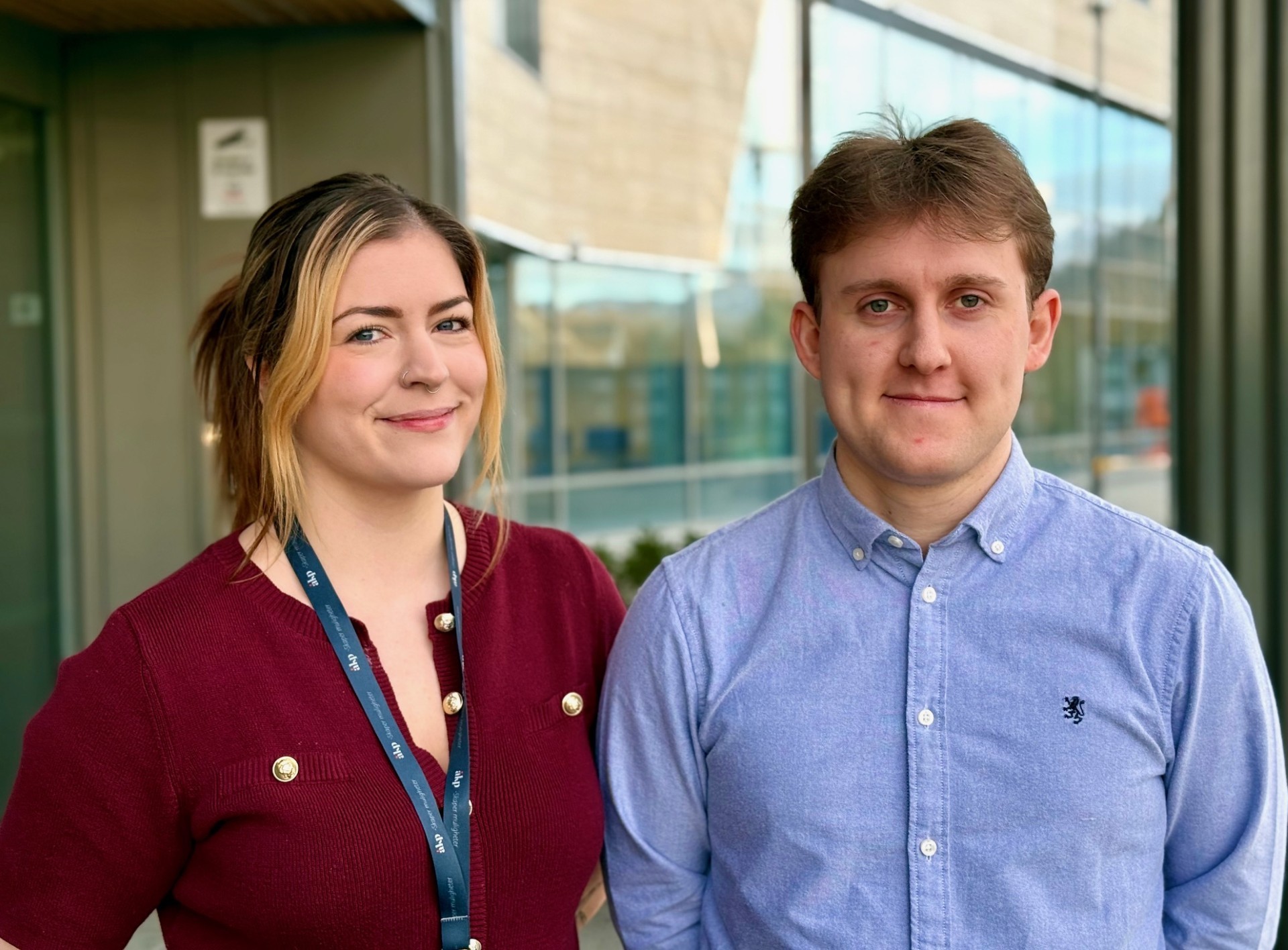 A person wearing a virtual reality headset stands in front of multiple screens, engaged in a digital experience.