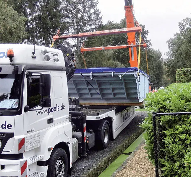 LKW mit Kranausleger setzt vorgefertigtes MLine Poolbecken auf Baustelle ab