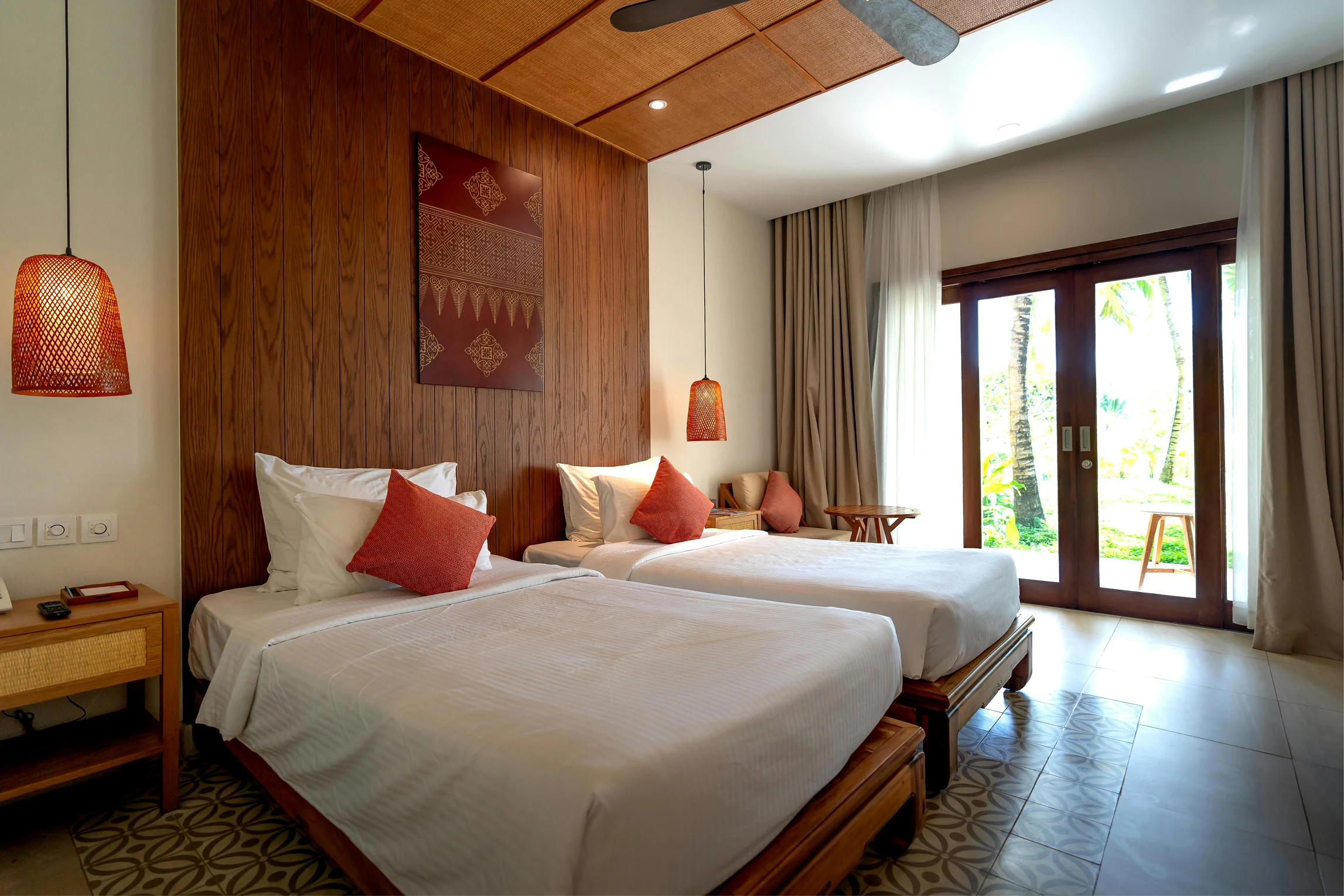 Deluxe sea view room with two beds, warm wooden details, and red accent pillows.