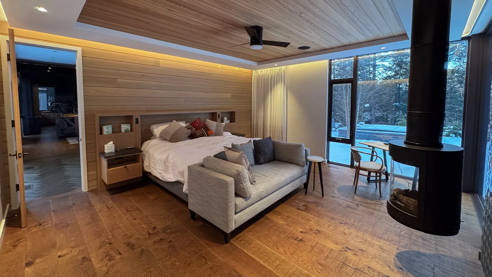 Luxury primary bedroom with king sized bed, floor to ceiling windows and floating fireplace.