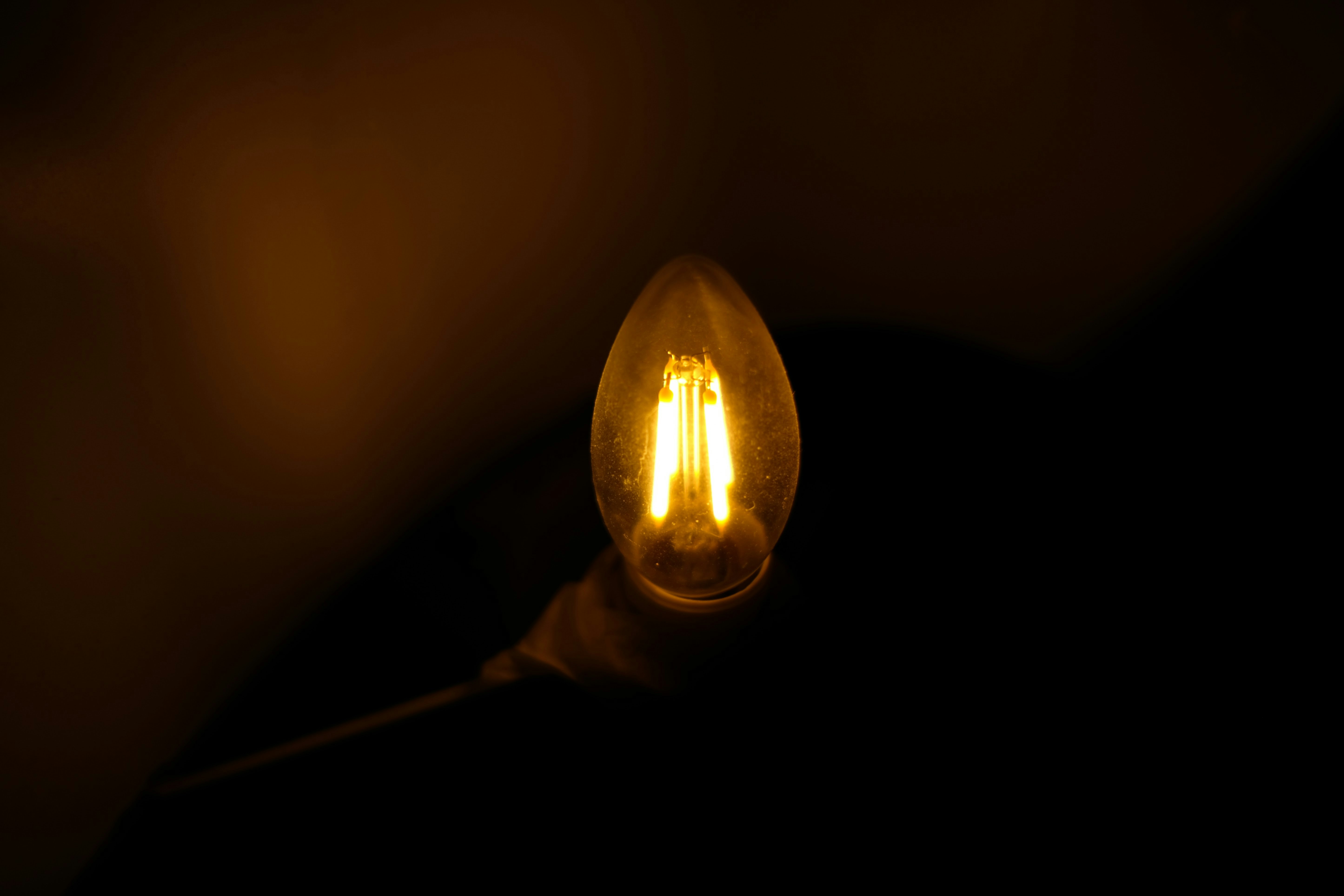 A lit candle-shaped light bulb in darkness.
