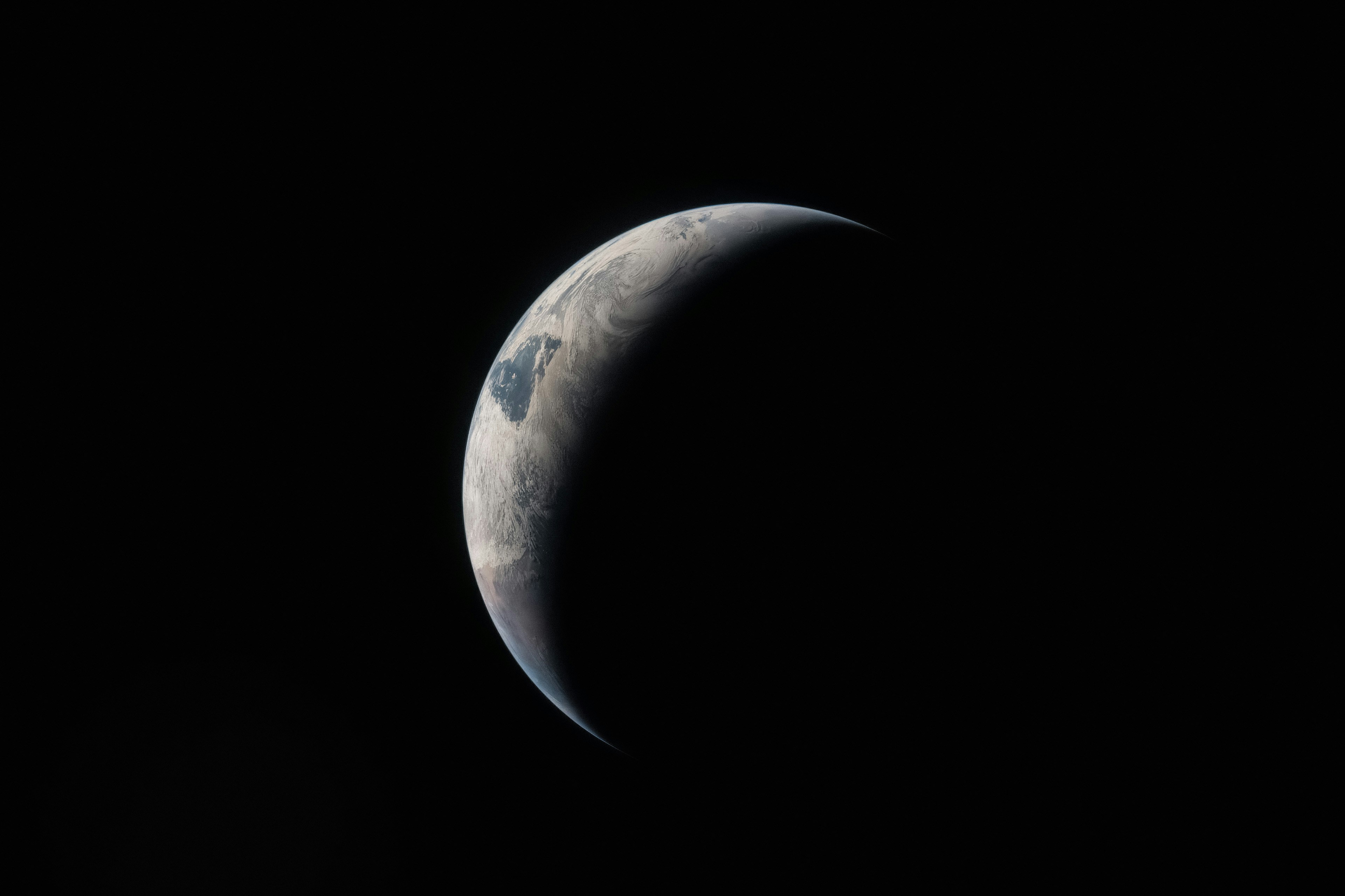 Crescent earth seen from space against black background