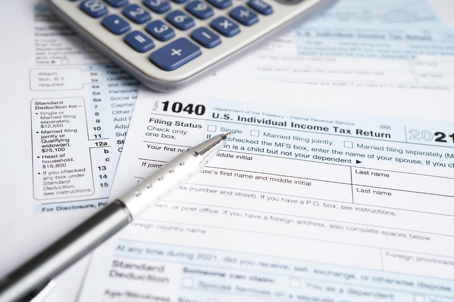 Formulario de declaración de impuestos individuales 1040 de EE. UU. con una pluma y calculadora, listo para ser completado