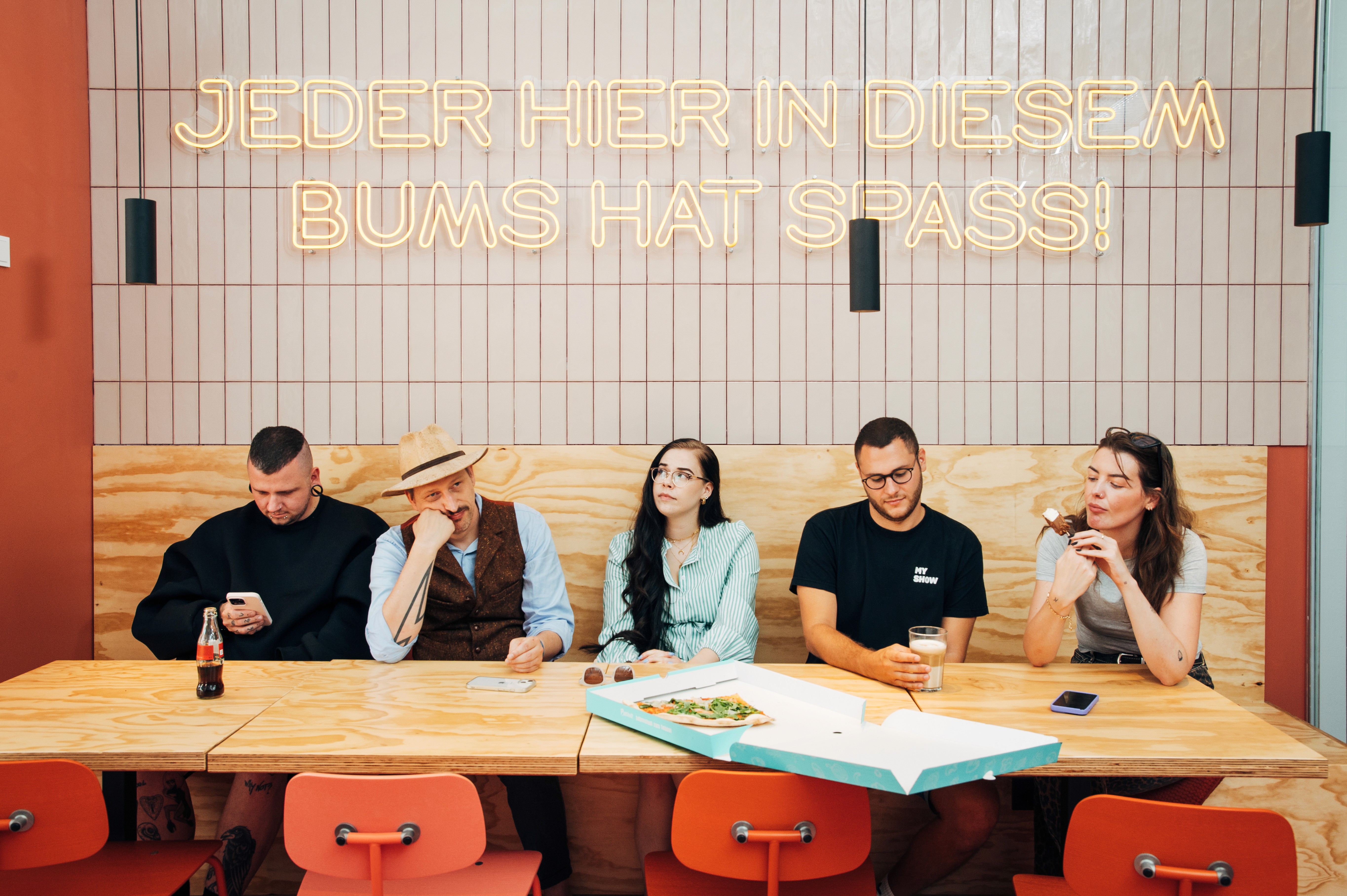 A diverse group of five people sitting at a table in a bright, modern setting, engaged in conversation.