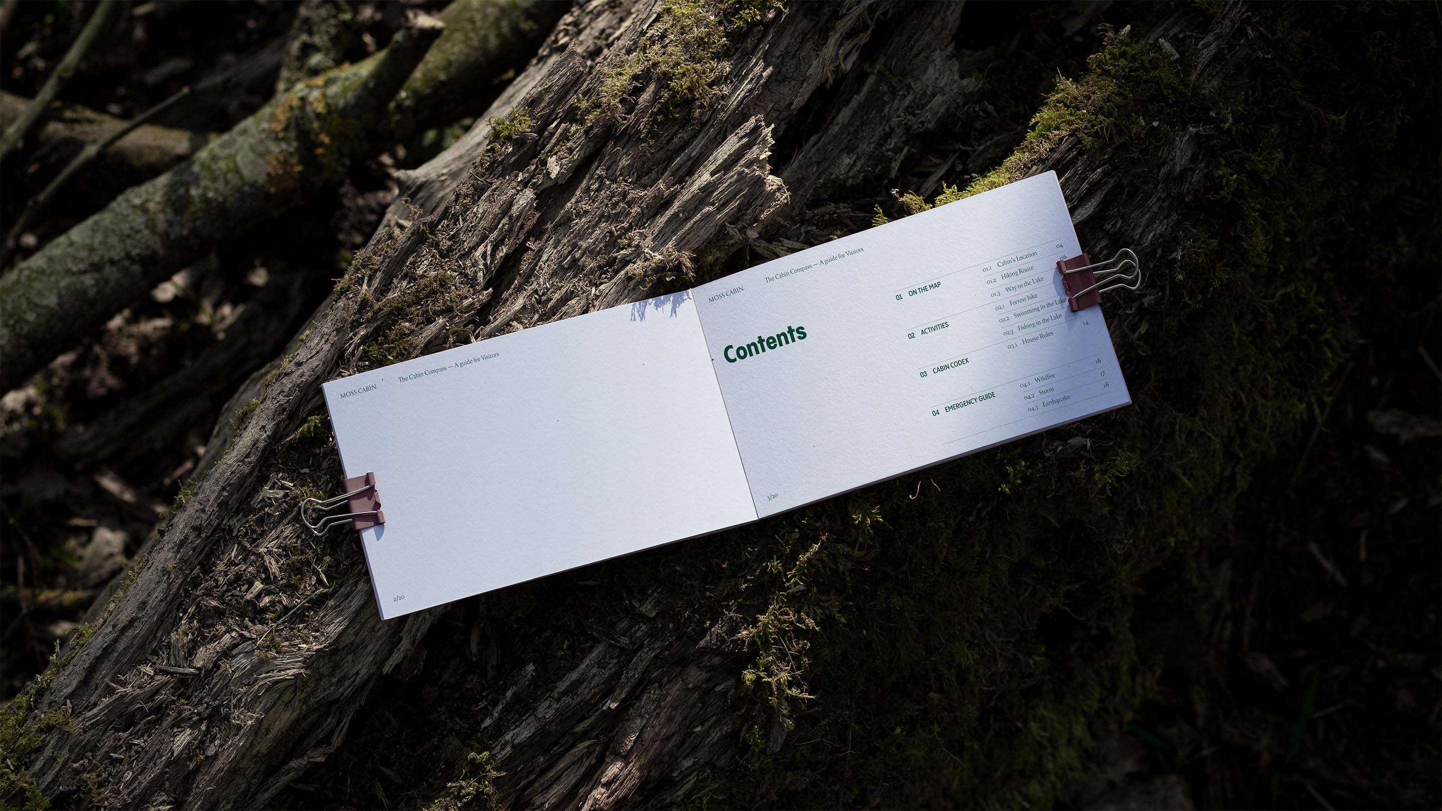 Moss cabin guide booklet spread showing contents page laid on mossy wood