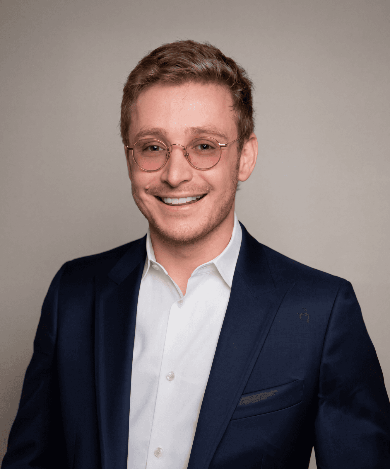 Young man in a suit smiling at the camera.