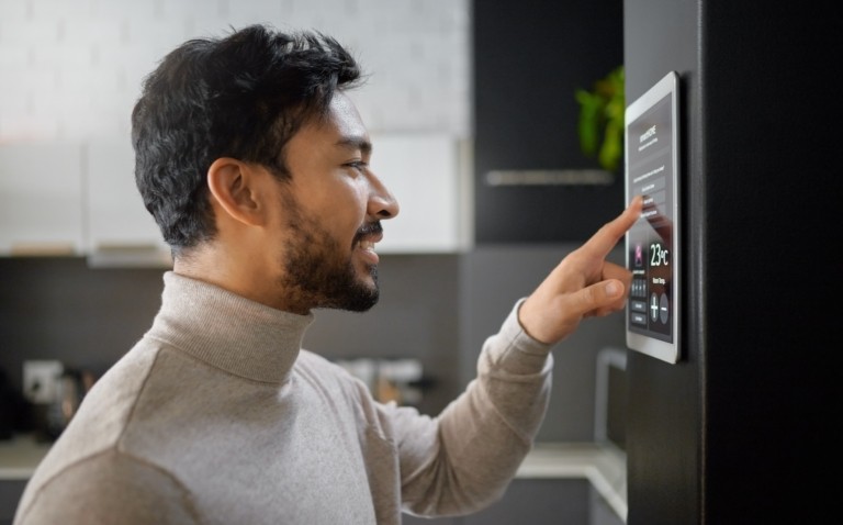 Man adjusting a smart energy control panel on a wall, representing energy management and cost-saving tips for care homes