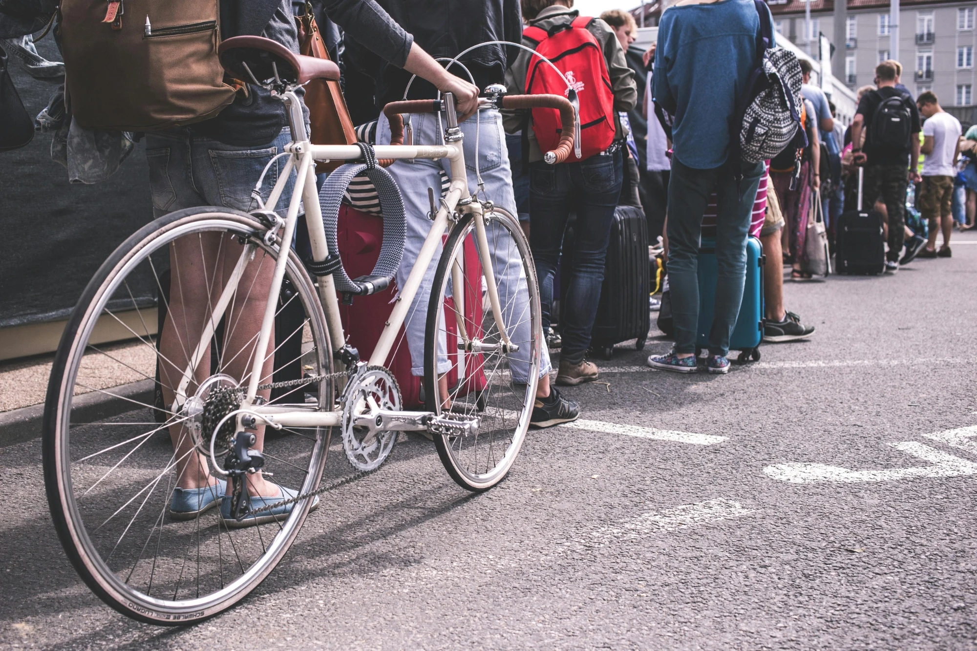 A group of people standing in line, each holding their bicycles, waiting for an event or activity to begin.