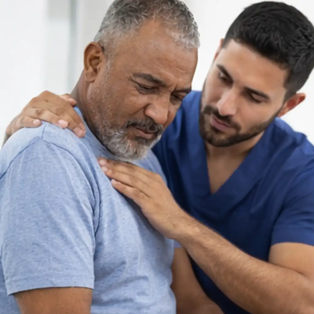 Chiropractor examining a male patient with shoulder pain during a treatment assessment in Draper, Utah