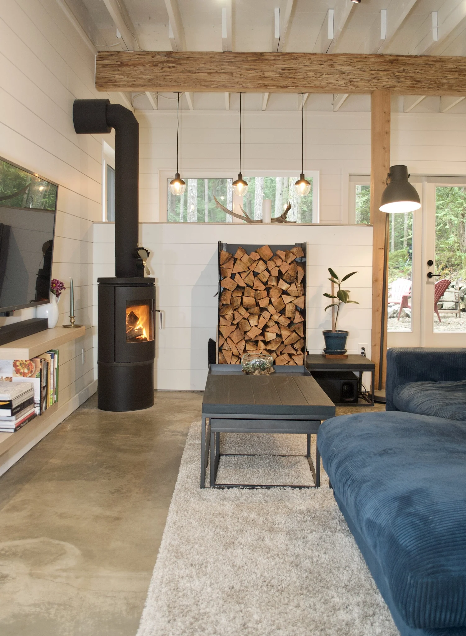 Modern two-story home with large glass windows, warmly lit interiors, and a balcony. Surrounded by trees and a manicured lawn at dusk. Cozy ambiance.