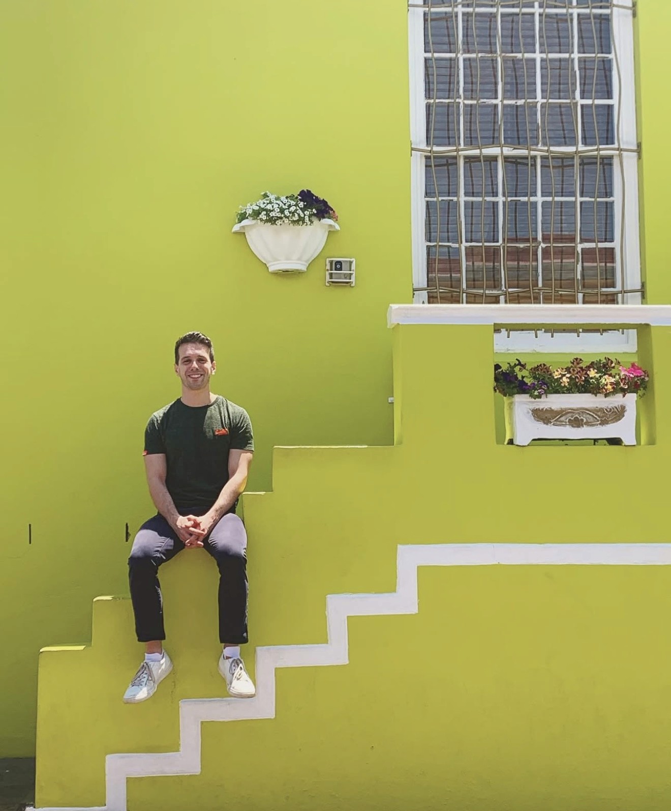 Adam seated against a vibrant lime green wall, smiling and relaxed