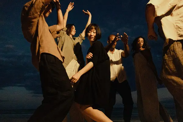 Grupo de personas bailando y divirtiéndose en la playa en Nomade Tulum México, con música en vivo tocando en el fondo