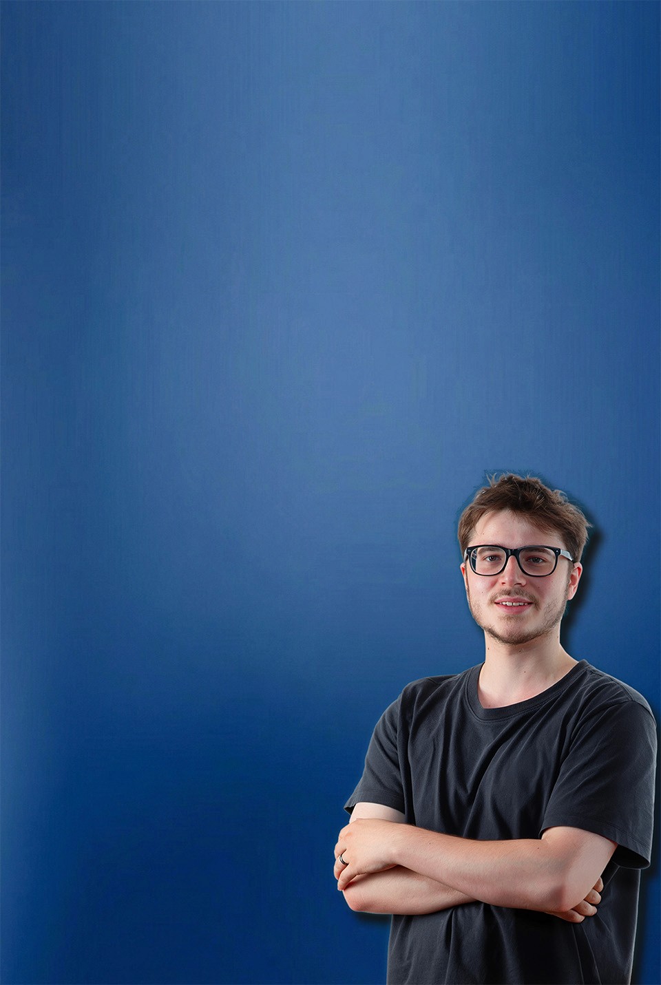 Porträt von mirudesign Gründer Mikail Althaus, der Werbeagentur aus Münster mit Brille und verschränkten Armen, lächelnd vor blauem Hintergrund.