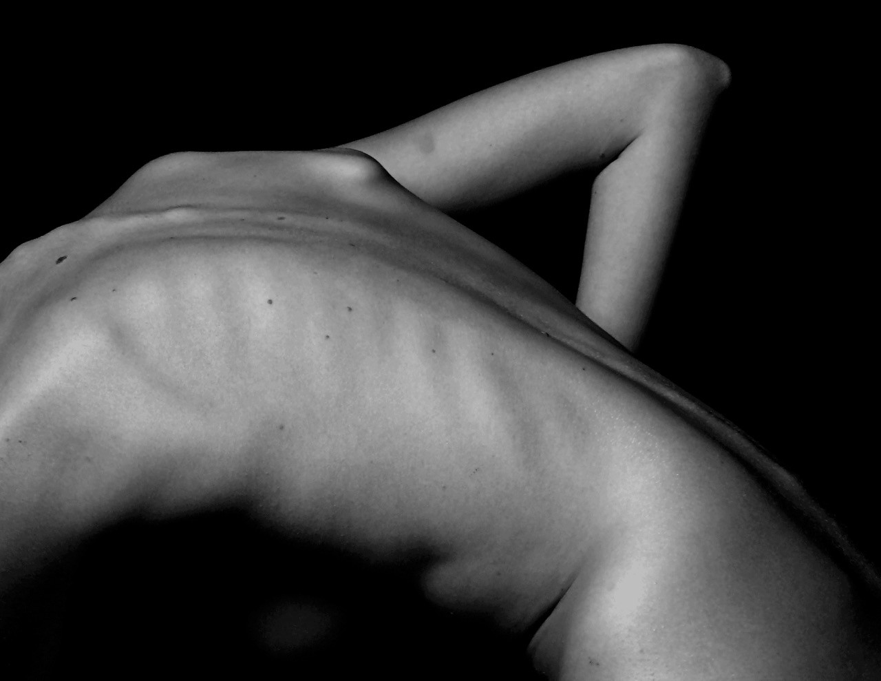 a naked woman sitting on a table with her back to the camera