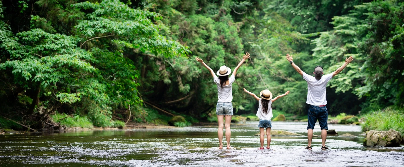 Family of three in the forest stading in a brook