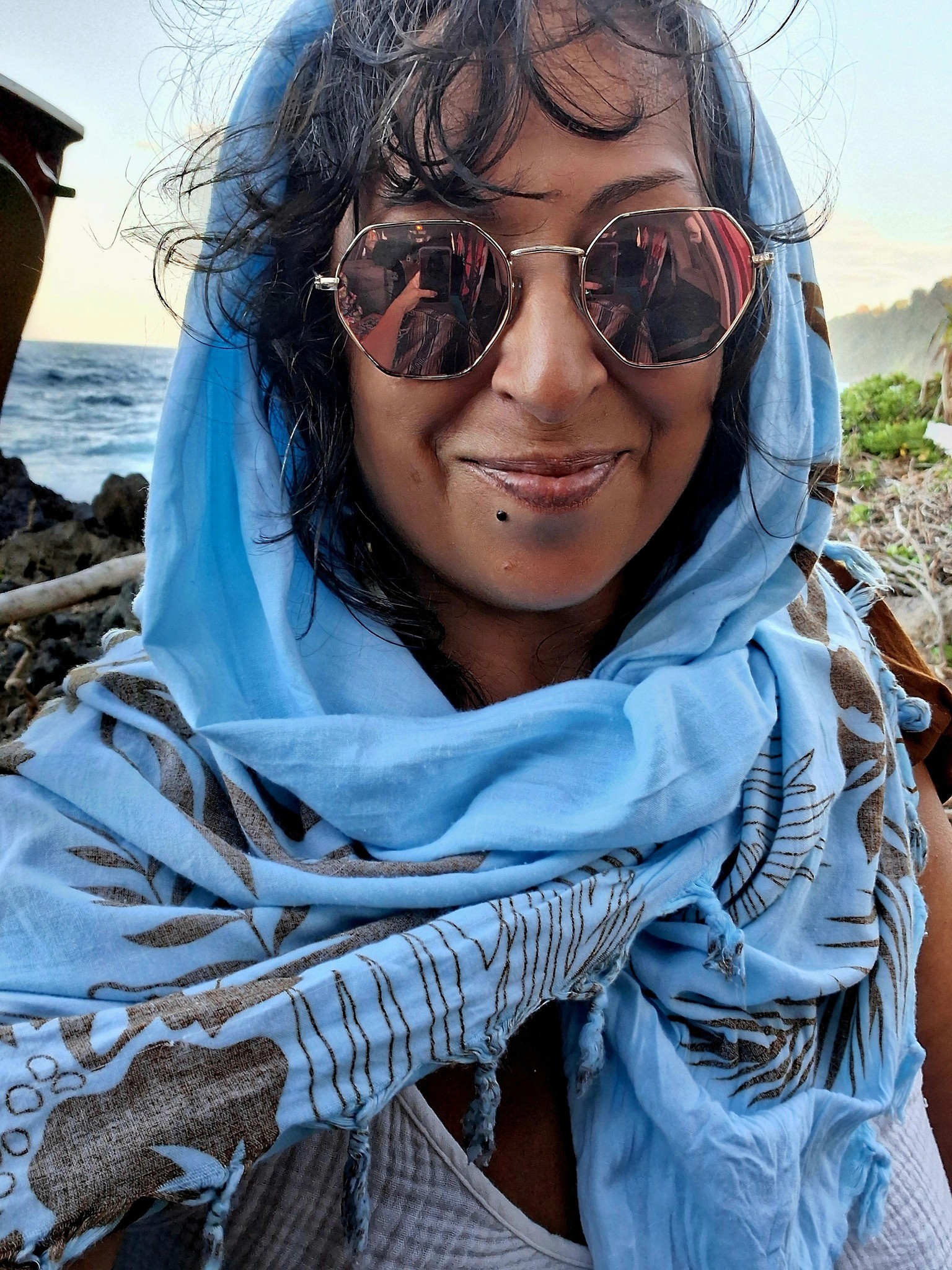 A smiling man in a suit and glasses sits at a table, with a modern office backdrop.